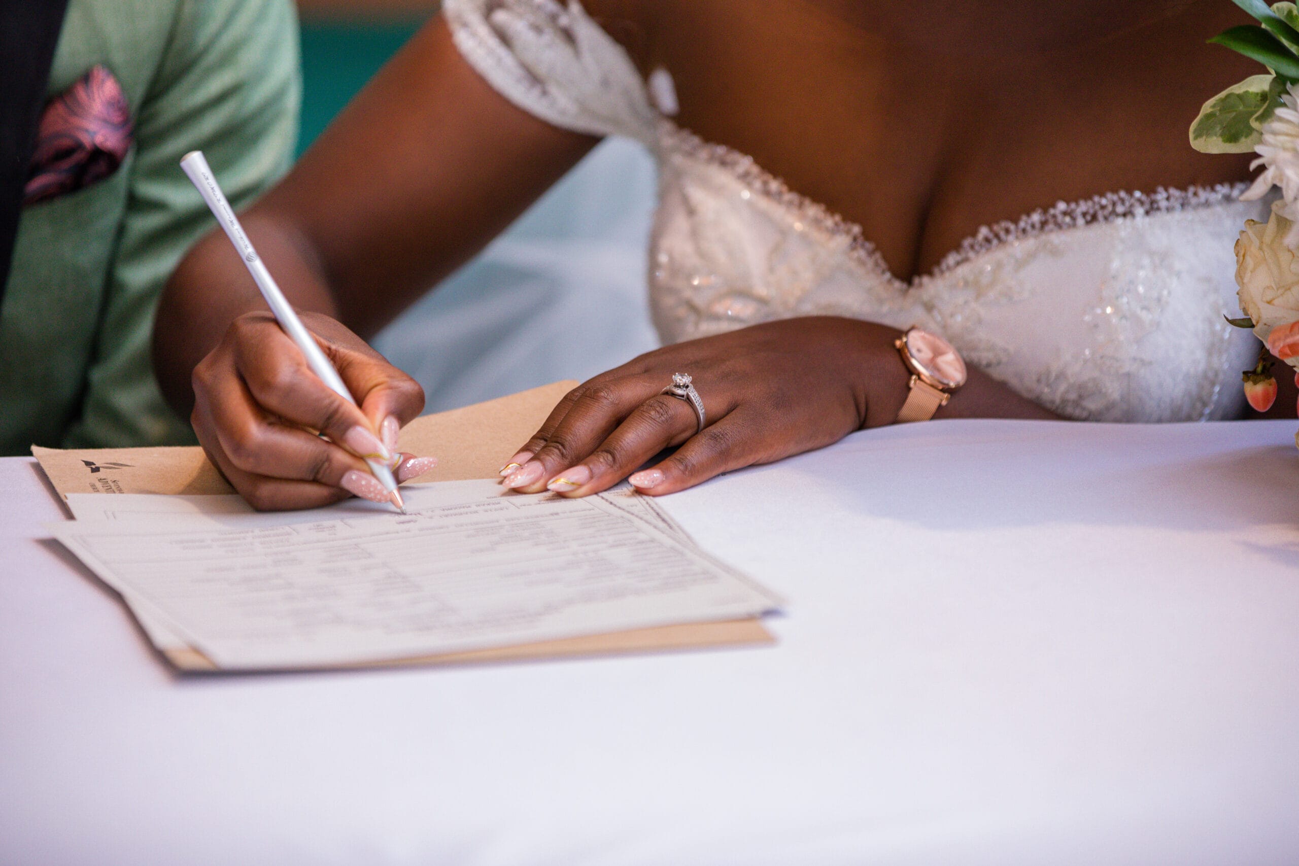 Main d'une femme en robe de mariée signant des documents